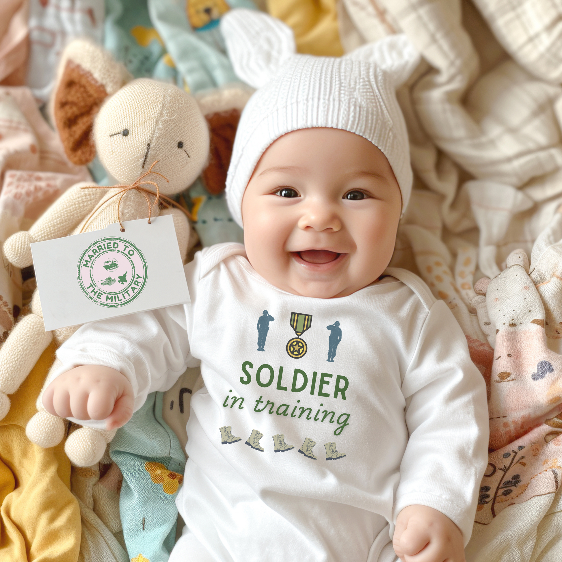 Infant baby bodysuit with 'Soldier in Training' design on the front and US flag in heart shape on the back, available in light blue, light pink, and white, sizes NB to 18 months.